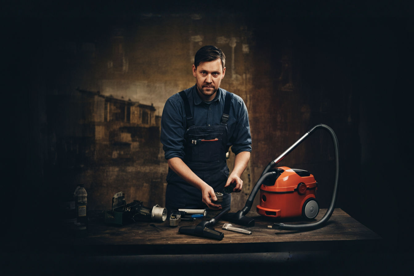 professional photograph of a man repairing his vacuum cleaner using spare parts on his workbench